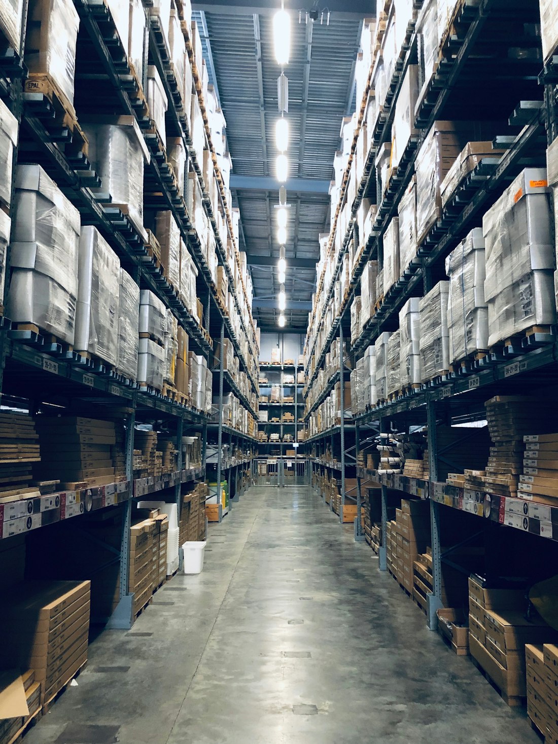 Allée d'un entrepôt logistique bordée de palettes stockées en hauteur