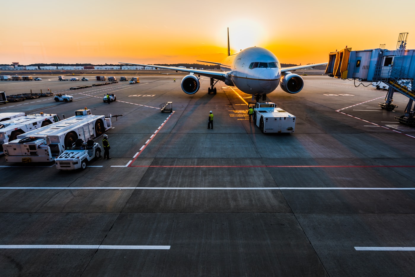 Avion au contact sur le tarmac au lever du soleil, véhicules de piste au premier plan